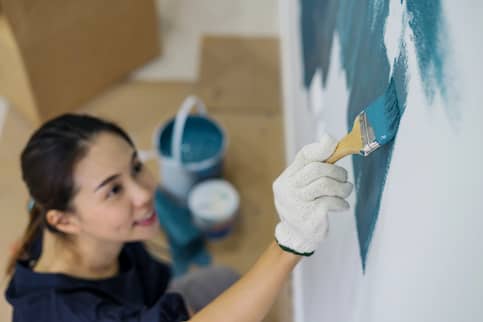 woman painting wall blue