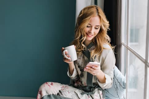 Woman Searching On iphone For Houses On Various Apps