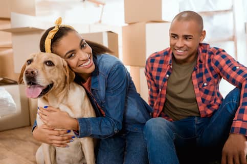 Happy couple with Golden Retriever relaxing amongst packed boxes in between moves.