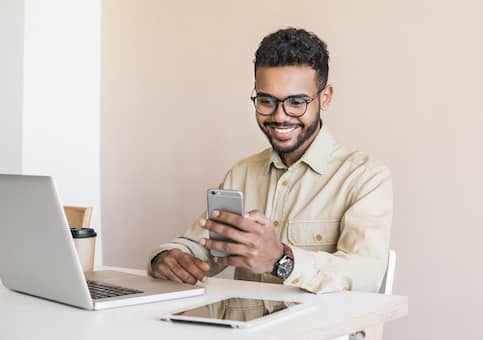 man on phone and laptop smiling
