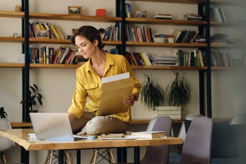 Young Woman Organizing Paperwork In Home Office 