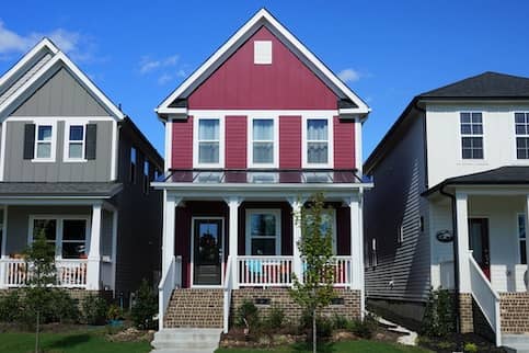 red house next to grey and white houses