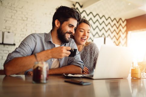 Couple drinking coffee and getting a mortgage in their living room. 