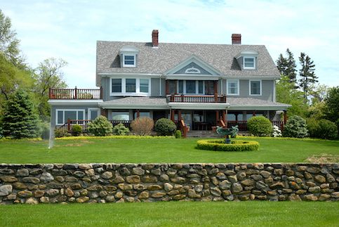 Front of large country home with green grass and a fountain.