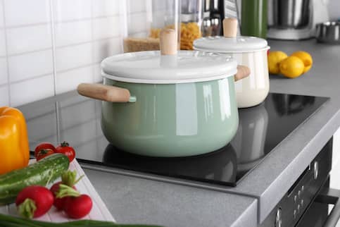 Green and white cooking pots on an electric stove.