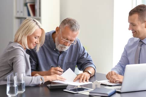 Woman and older man cosigning mortgage documents.