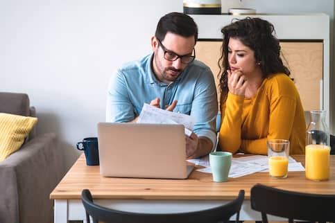 Worried couple looking at their bills at kitchen table