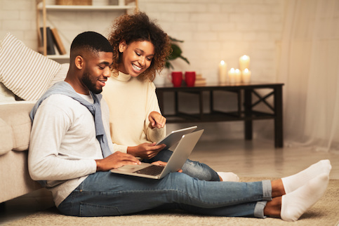 Woman reading on couch, man sitting on floor with laptop.