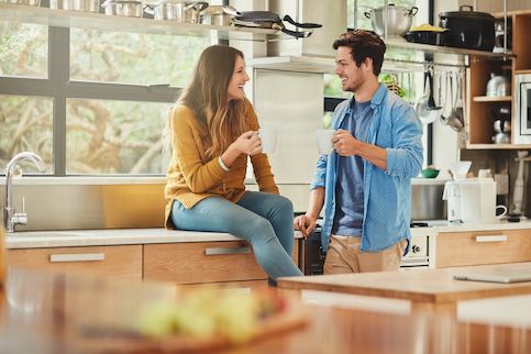 Couple discussing their new house in their new kitchen, drinking coffee. 