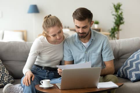 Couple On Couch Looking At Documents