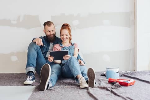 Couple painting home while looking at a tablet