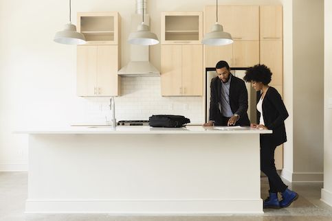 African American Couple Reading Documents In Renovated Kitchen 