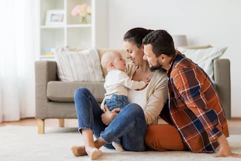 Couple Sitting On Floor With New Baby