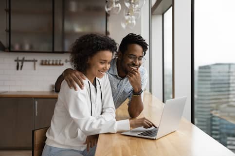 Couple viewing laptop in loft apartment kitchen.