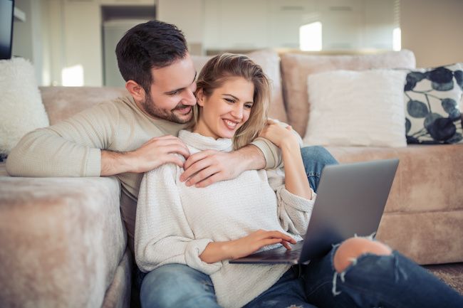 Couple looking at the computer together on the couch.
