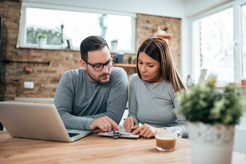 Couple doing paperwork at kitchen counter.