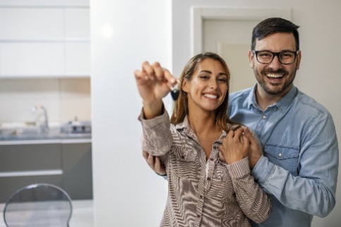 Young couple holding keys in new home.