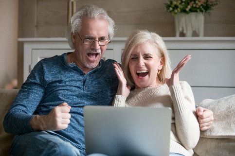 Excited older couple looking at a laptop and cheering.