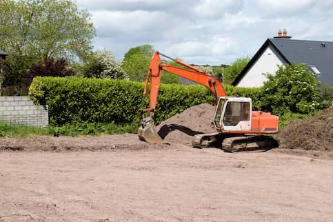Orange bulldozer picking up dirt for new plot of land.