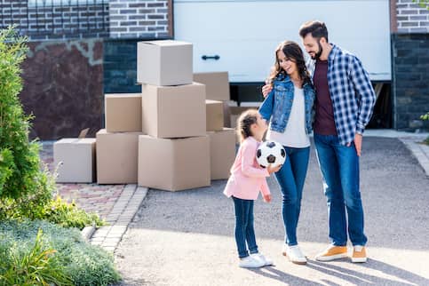 family in driveway near moving boxes and young girl holding soccer ball