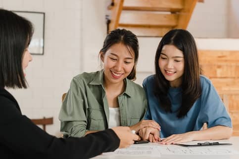 Female couple signing paperwork with an agent.