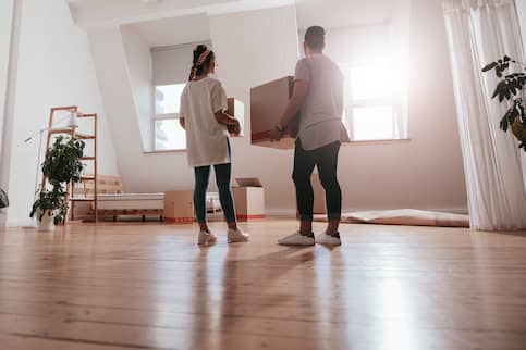 Gen Z couple holding boxes in empty room