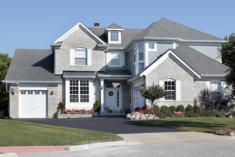 grey house with basketball net and flowers out front