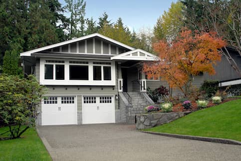 Grey white suburban house with green grass long driveway