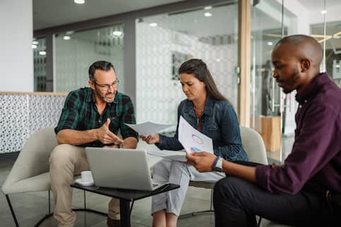 A group of three people discussing finances and business.