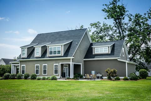 grey house with large yard and patio set