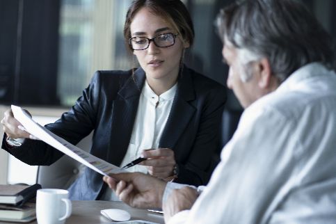 Business woman presenting a document to an older gentleman.