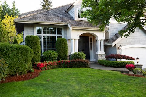 Home with green lawn and arched entryway. 