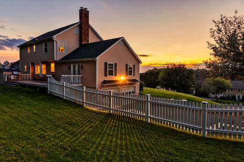 Home with large green lawn at sunset.