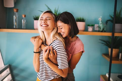 Young lesbian first time home buyers embracing smiling.