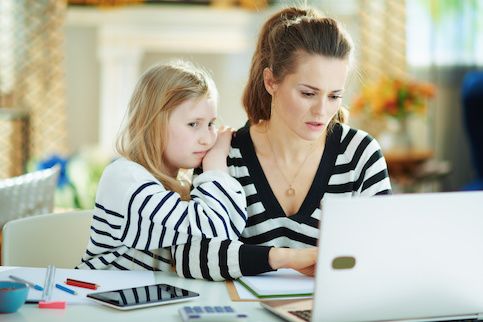 mother calculating finances on laptop with daughter leaning on shoulder