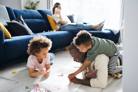 Multi Racial Family Relaxing And Playing In Living Room 