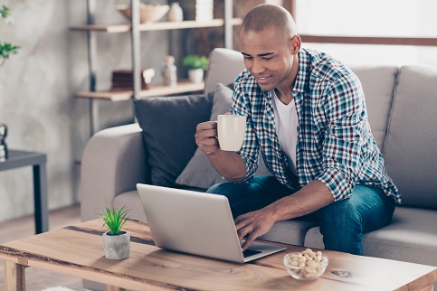 Man on couch with coffee and a laptop