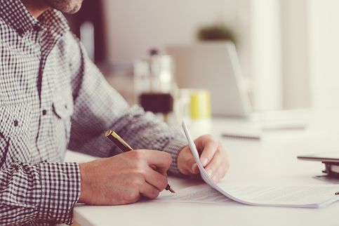 Man signing a thick document. 