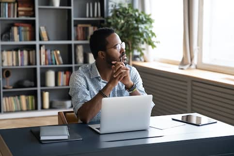 Man thinking in office space with computer.