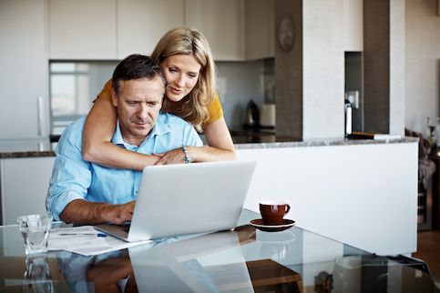 Middle age couple paying bills in kitchen. 