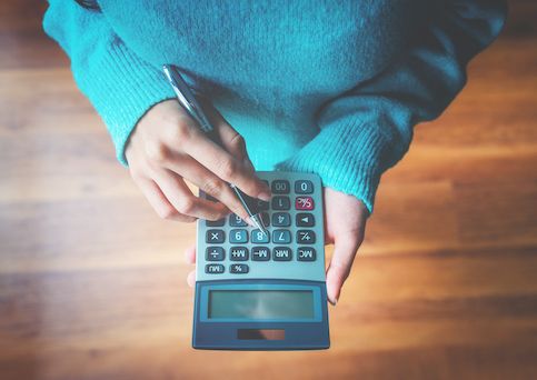 Person typing in a calculator over view of hardwood floor