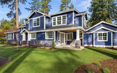 Front of blue house surrounded by green grass