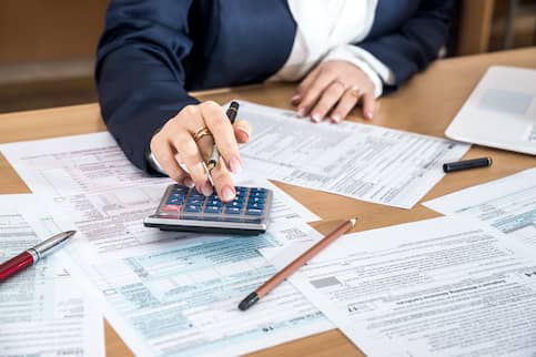 woman doing taxes with calculator and pen