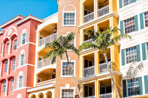 Condos, condominiums colorful, orange yellow multicolored buildings facade exterior with windows, palm trees, real estate property in Spain.