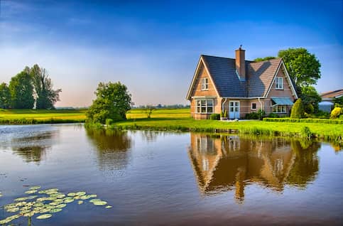 Red brick house next to pond.