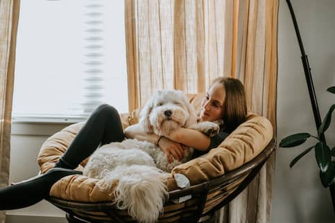 Young Woman In Papasan Chair With Dog Relaxing 