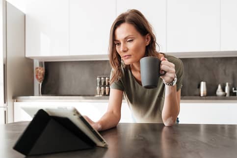 Woman reading reviews of Select Home Warranty in kitchen