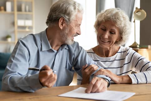senior couple smiling and signing documents together