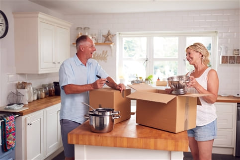 Senior Couple Packing Boxes In Kitchen