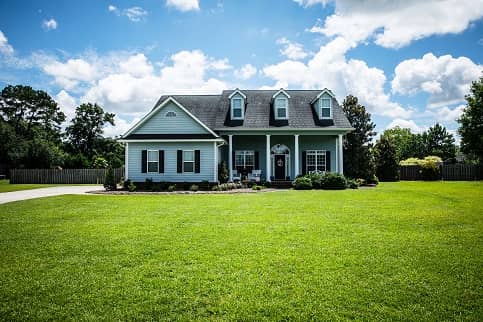 Small Blue House On Large Green Lawn